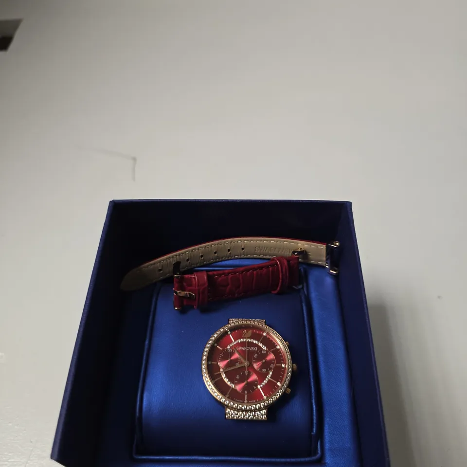 SWAROVSKI WRISTWATCH WITH RED DIAL AND CRYSTAL-SET BEZEL – IN BLUE PRESENTATION BOX