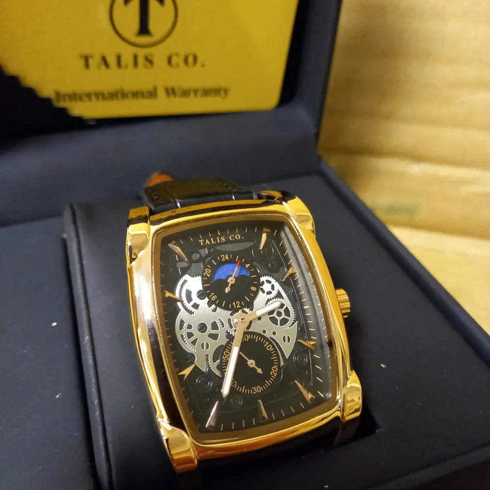 MENS TALIS CO WATCH, CHRONOGRAPH MOVEMENT. BLACK LEATHER STRAP, GOLD FRAME, SLEEK BLACK/SILVER SKELETON DIAL