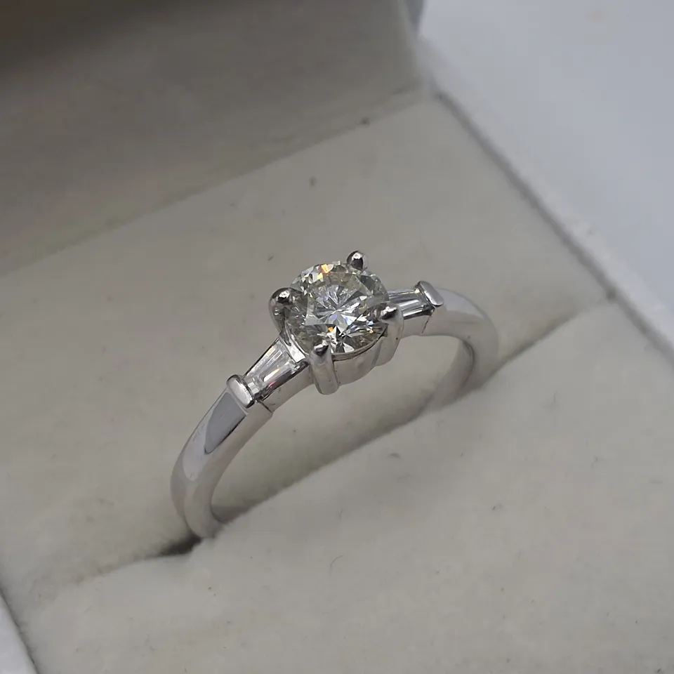 18CT WHITE GOLD RING SET WITH A NATURAL DIAMOND TO THE CENTRE AND A BAGUETTE TO EACH SHOULDER