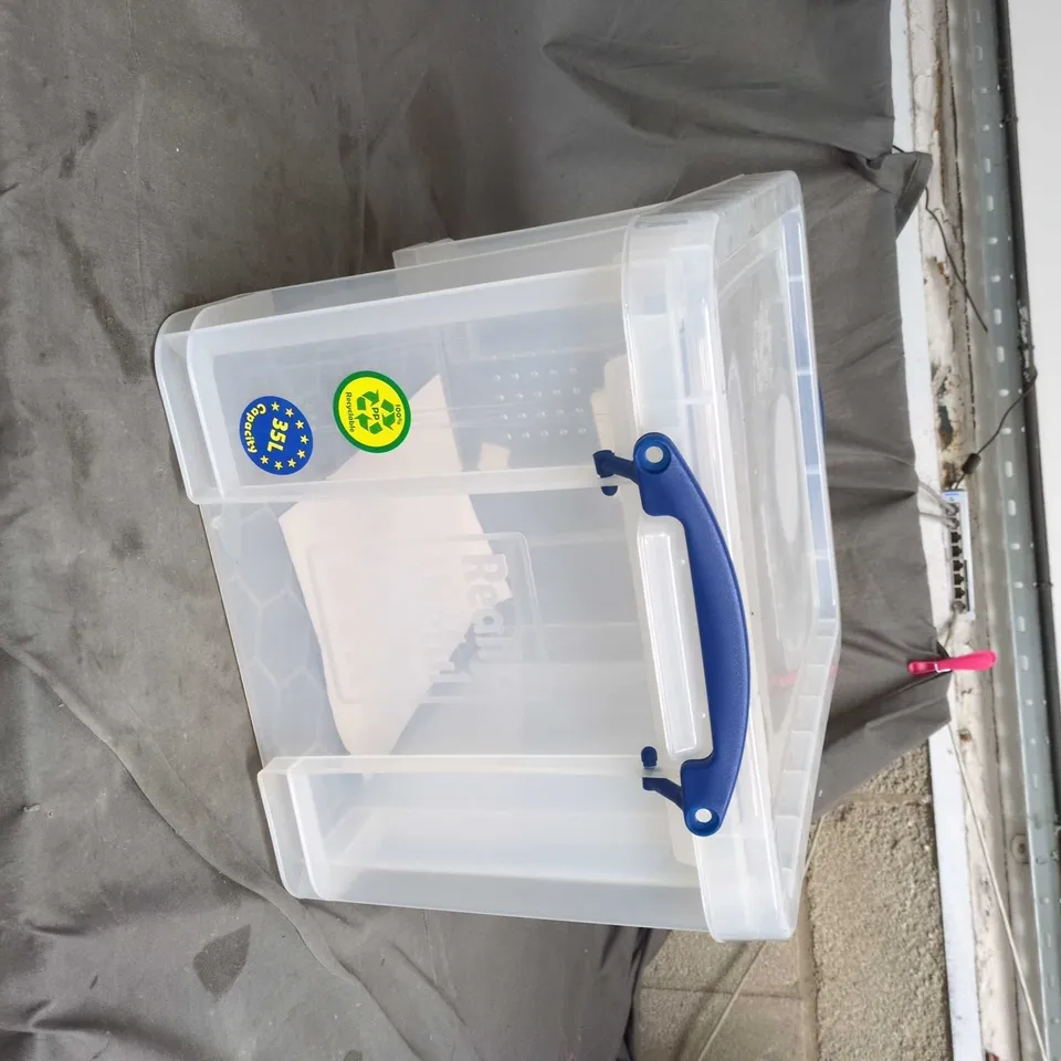 TRANSPARENT PLASTIC STORAGE BOX WITH BLUE CARRY HANDLE AND LID SZIE UNSPECIFIED .