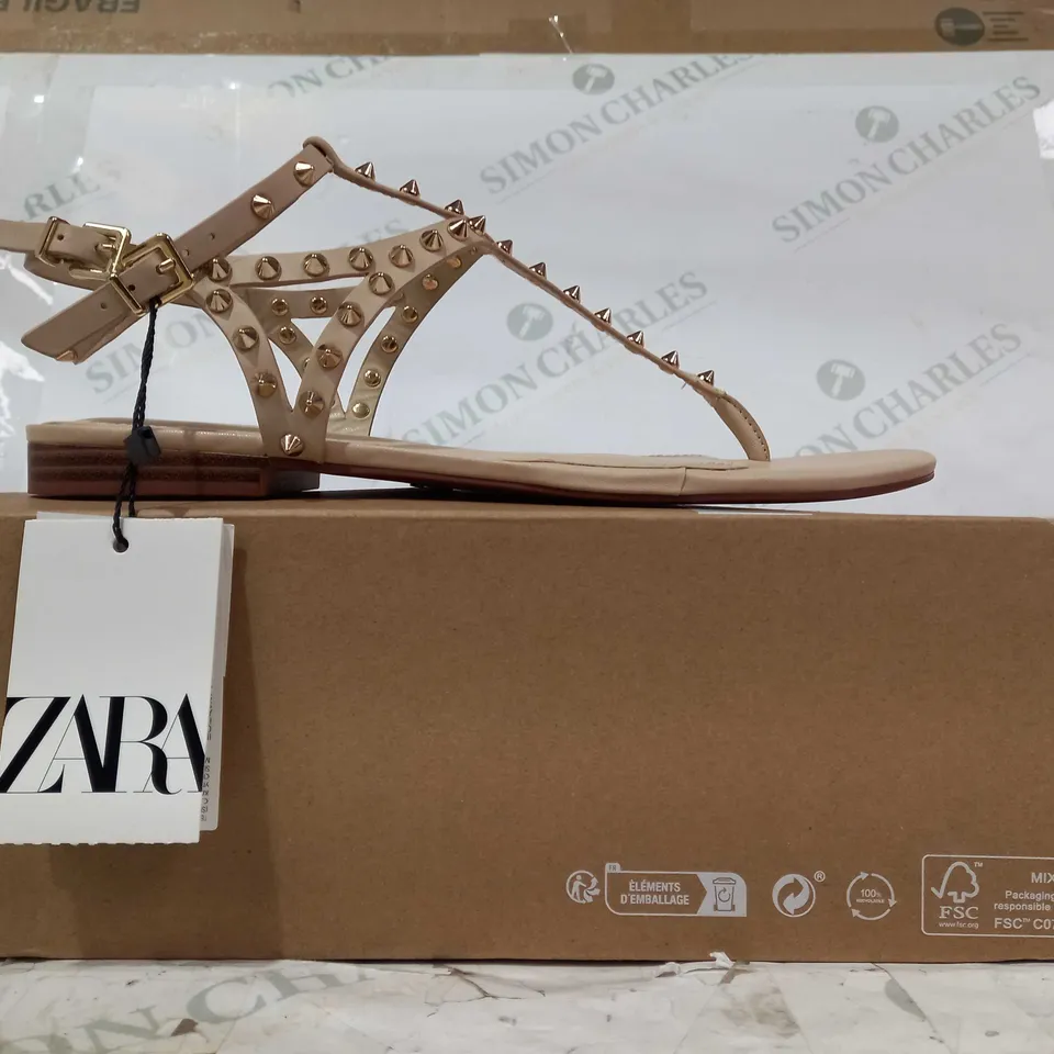 BOXED PAIR OF ZARA FLAT SANDALS IN NUDE COLOUR W. GOLD EFFECT SPIKE STUDS EU SIZE 38