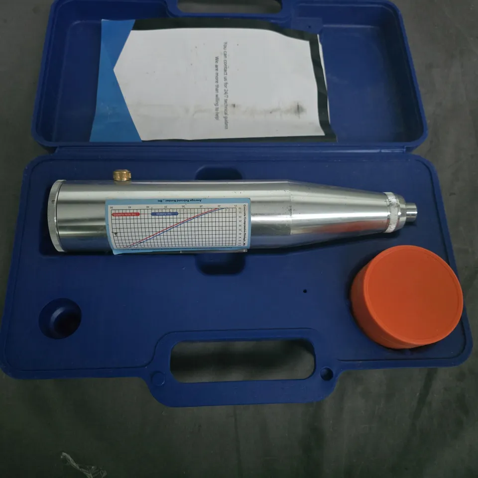 Handheld metal measuring instrument in blue case with orange cap