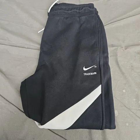 NIKE TRACKPANTS, BLACK WITH WHITE DIAGONAL STRIPE AND SWOOSH – UK MEDIUM (M)
