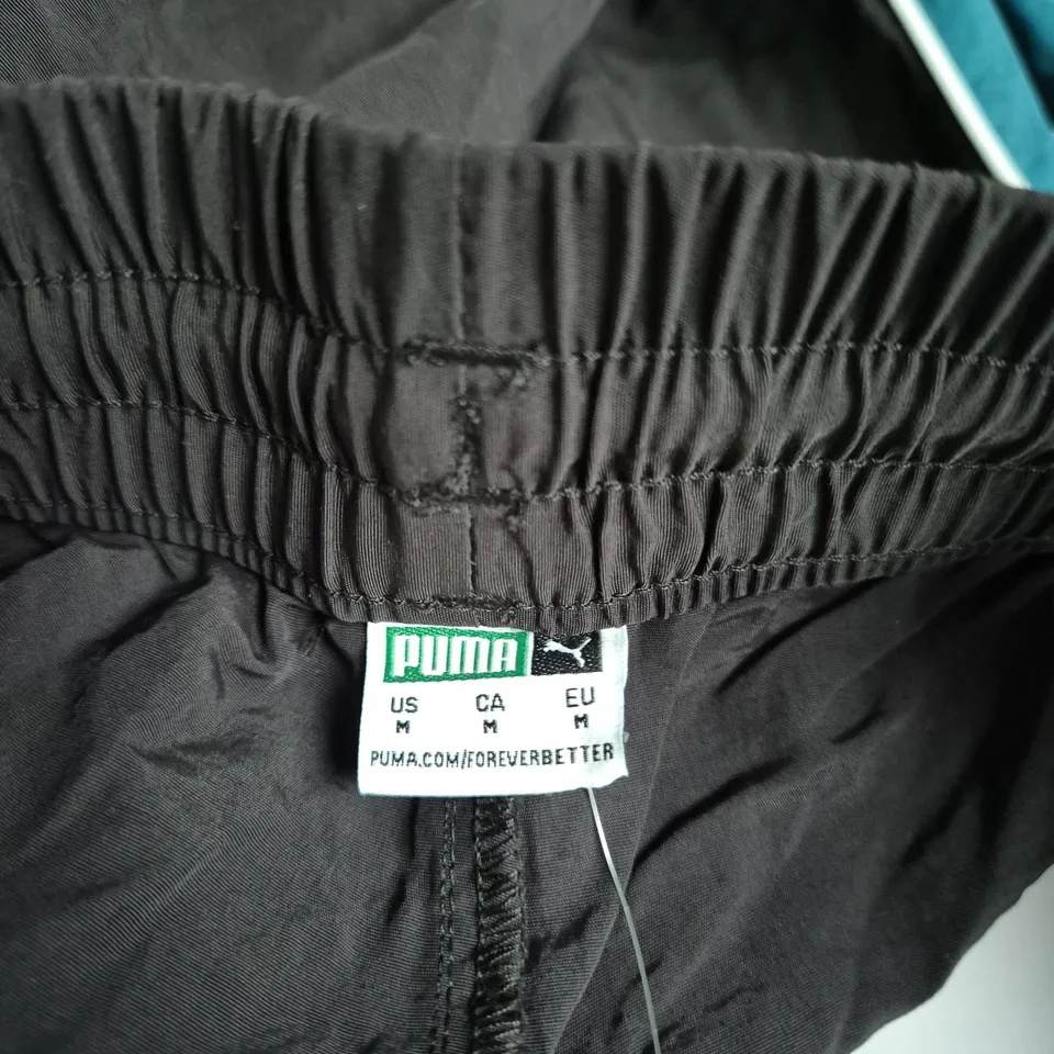 PUMA RELAXED FIT STRAIGHT LEG TRACK PANTS – BLACK WITH TEAL SIDE STRIPE SIZE UK M