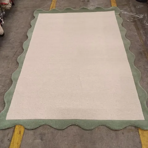BEIGE AREA RUG WITH SCALLOPED GREEN BORDER APPROXIMATELY 218 CM X 150 CM
