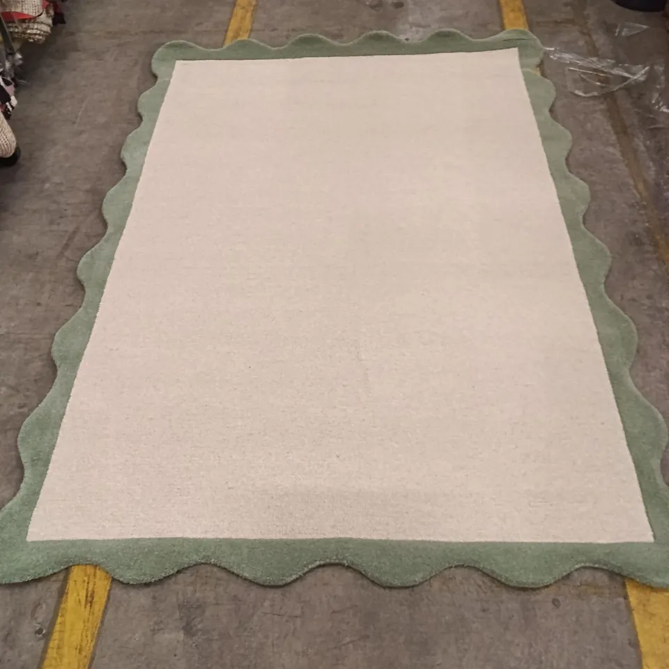 BEIGE AREA RUG WITH SCALLOPED GREEN BORDER APPROXIMATELY 218 CM X 150 CM