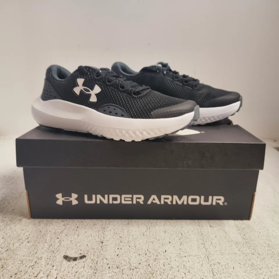 BOXED PAIR OF UNDER ARMOUR BGS SURGE 4 TRAINERS IN BLACK/WHITE SIZE UK 3