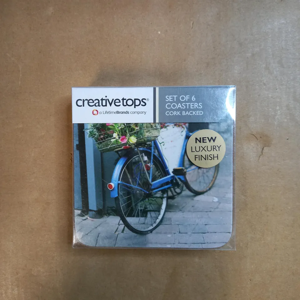 BOX OF APPROXIMATELY 30 PACKS OF CREATIVE TOPS SET OF 6 CORK BACKED COASTERS IN A VINTAGE BICYCLE DESIGN 