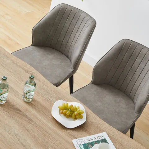 A BOXED PAIR OF GREY FAUX LEATHER UPHOLSTERED SIDE CHAIRS