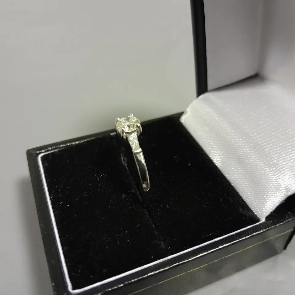 18CT WHITE GOLD RING SET WITH A NATURAL DIAMOND TO THE CENTRE AND A BAGUETTE TO EACH SHOULDER