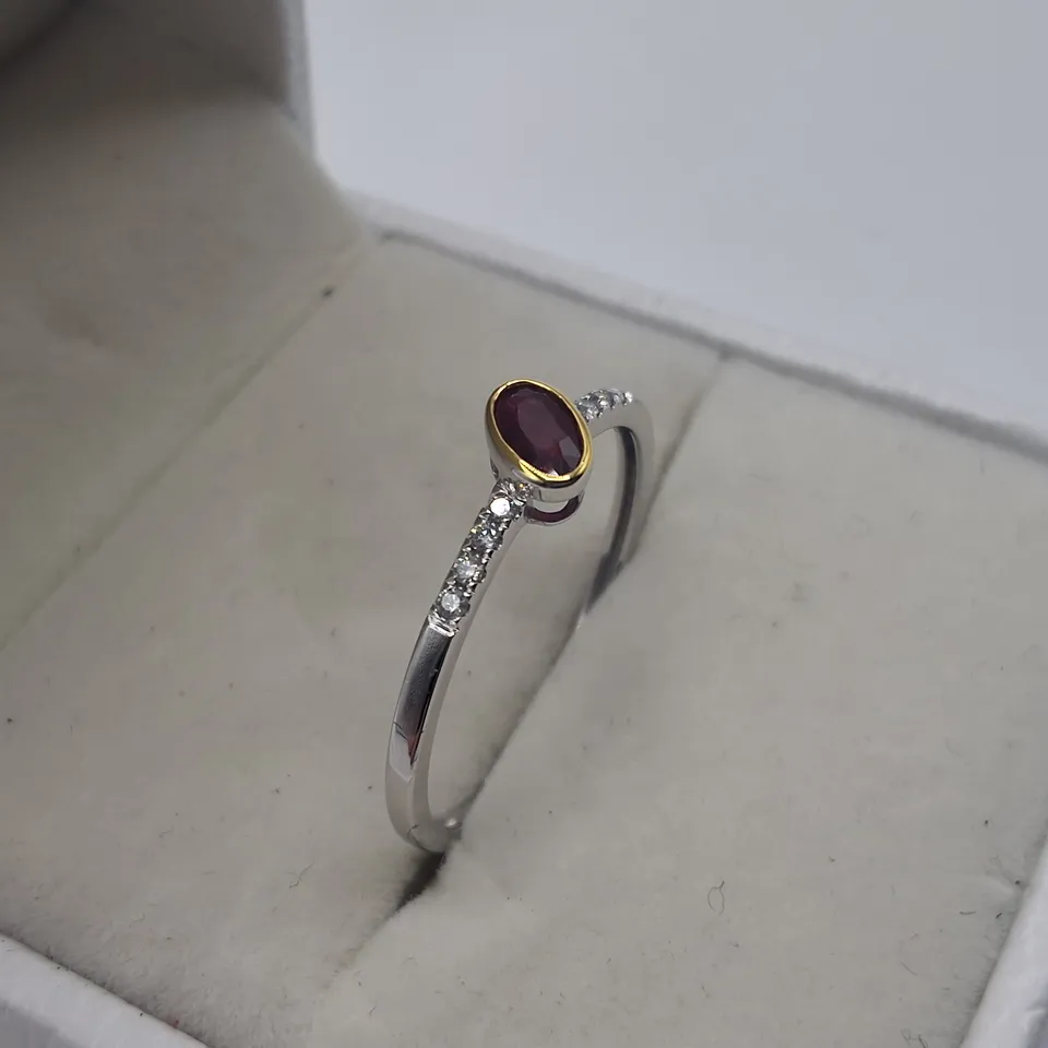 18CT GOLD RING WITH AN OFF-SET ROB OVER OVAL CUT RUBY AND NATURAL DIAMONDS TO EACH SHOULDER