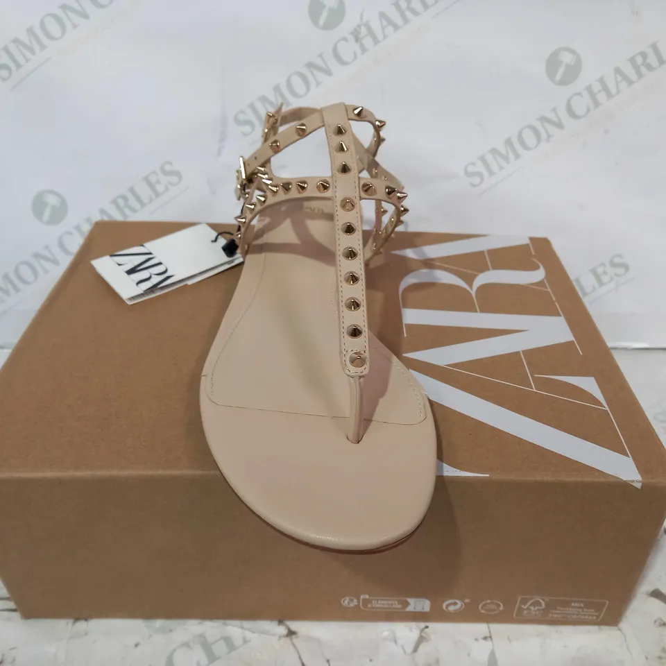 BOXED PAIR OF ZARA FLAT SANDALS IN NUDE COLOUR W. GOLD EFFECT SPIKE STUDS EU SIZE 38