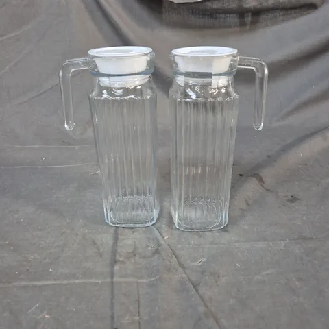 PAIR OF RIBBED GLASS PITCHERS WITH WHITE LIDS