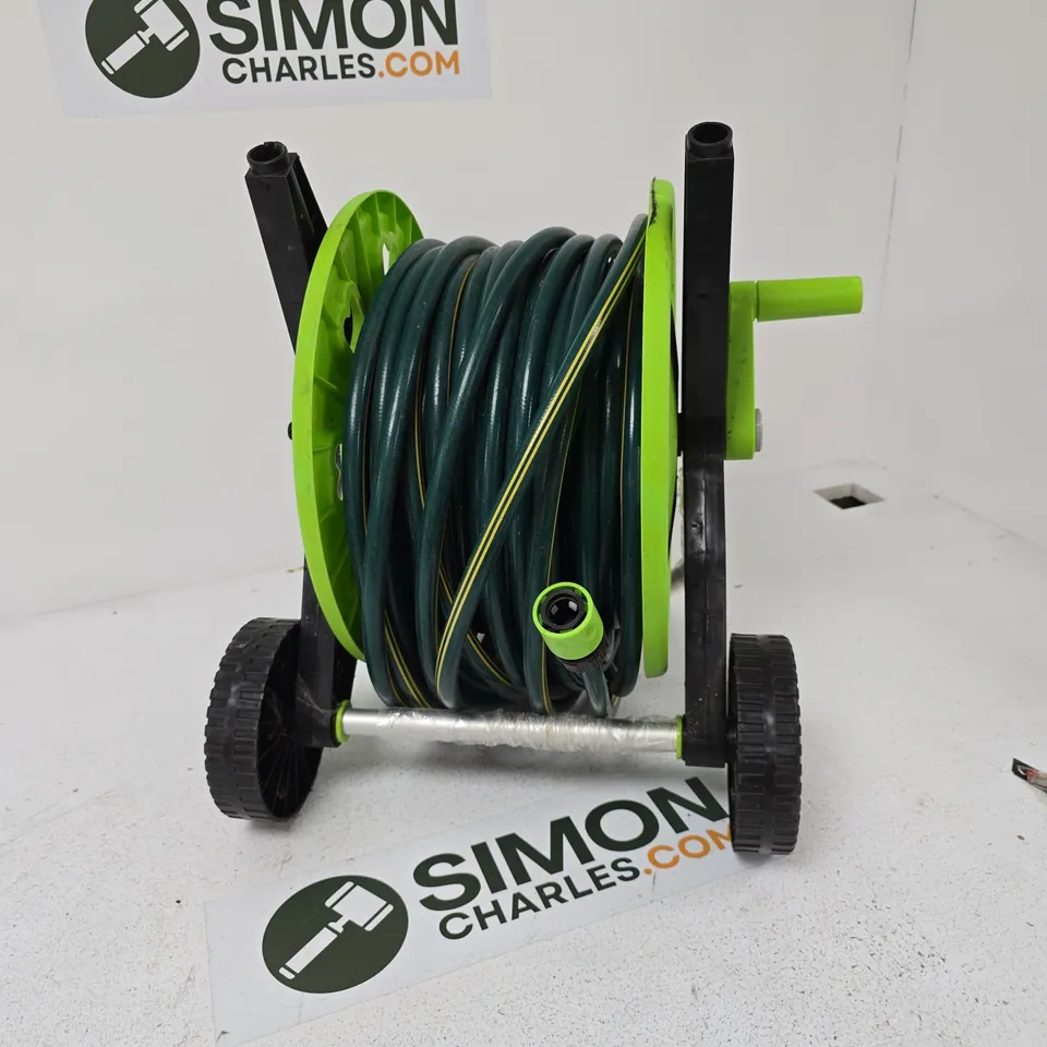 GREEN GARDEN HOSE REEL ON WHEELED TROLLEY WITH COILED HOSE