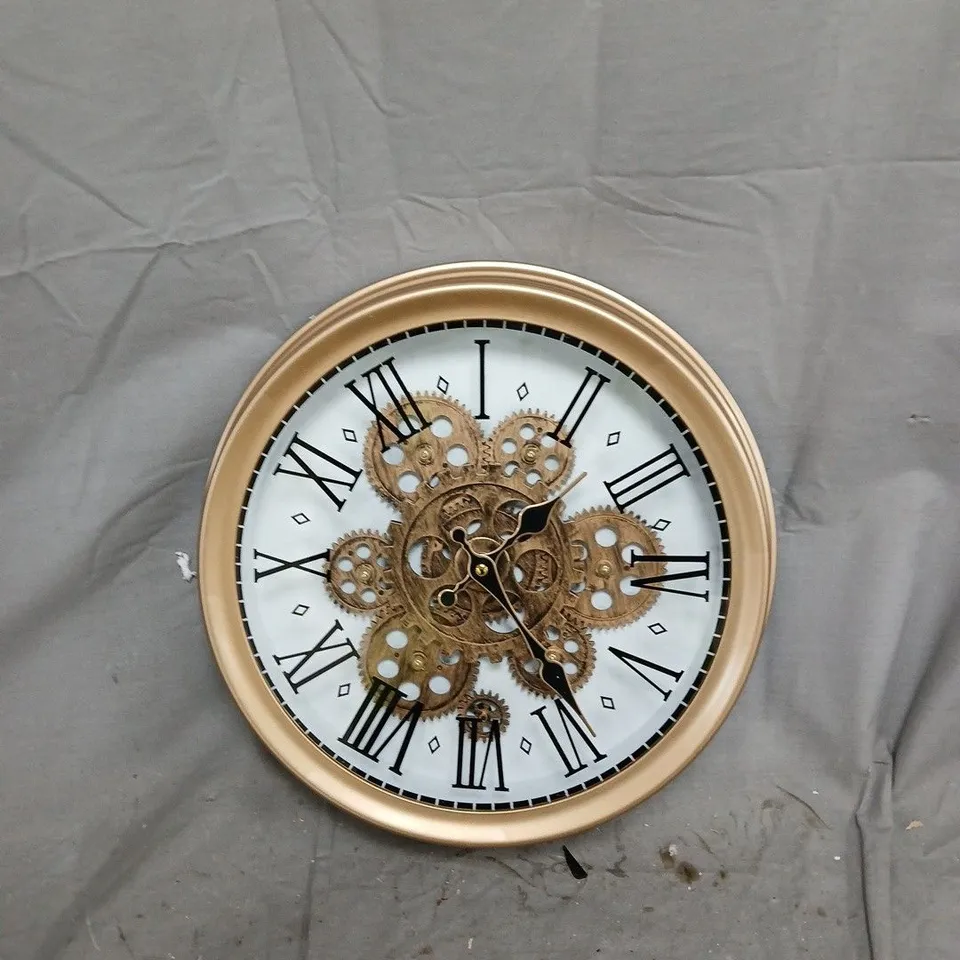 ROUND BRASS-TONE WALL CLOCK WITH EXPOSED GEARS AND ROMAN NUMERALS