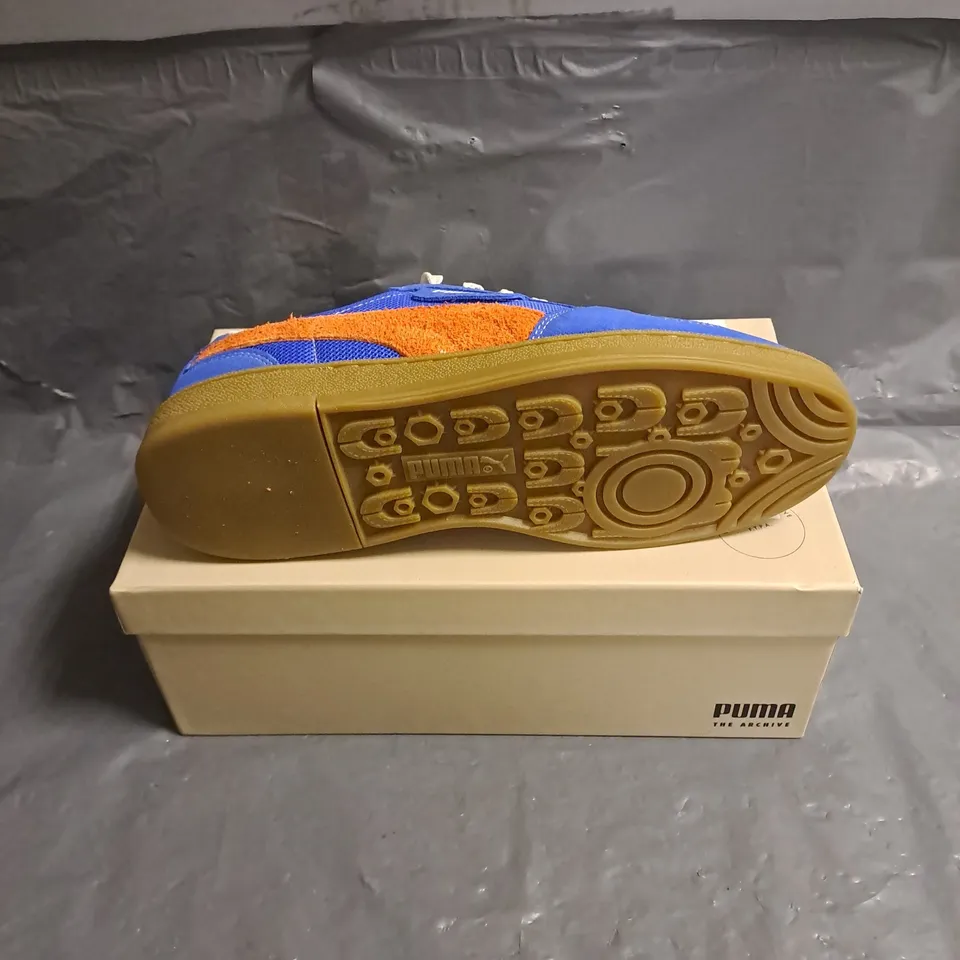 BOXED PAIR OF PUMA SUPER TEAM HANDY TRAINERS IN ULTRA BLUE/RICKIE ORANGE SIZE 7