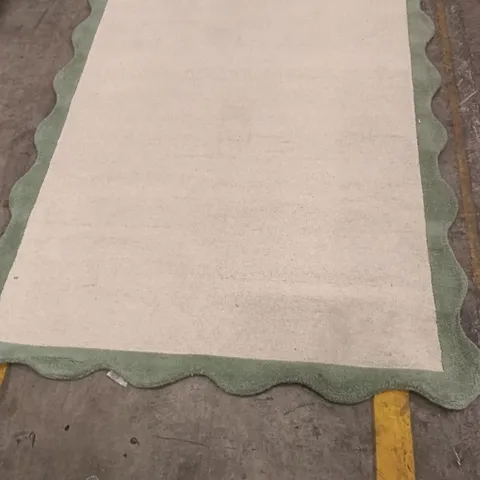 RUG – CREAM CENTRE WITH GREEN SCALLOPED BORDER APPROXIMATELY 216 CM X 151 CM