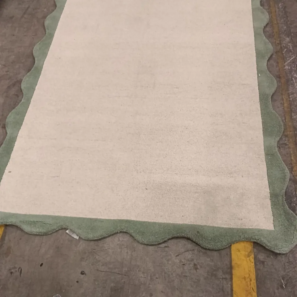 RUG – CREAM CENTRE WITH GREEN SCALLOPED BORDER APPROXIMATELY 216 CM X 151 CM