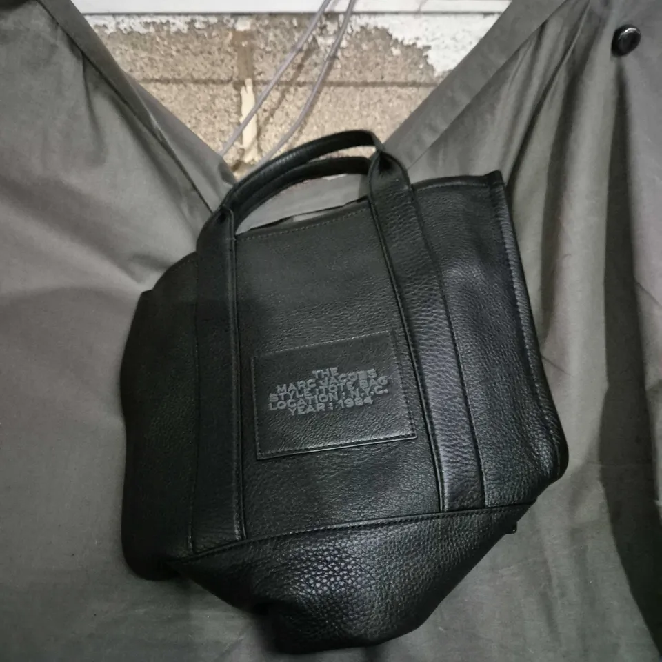 The Marc Jacobs Tote Bag – Black Leather with Front Patch Reading 'THE MARC JACOBS STYLE TOTTE BAG LOCATION NYC YEAR 1984'