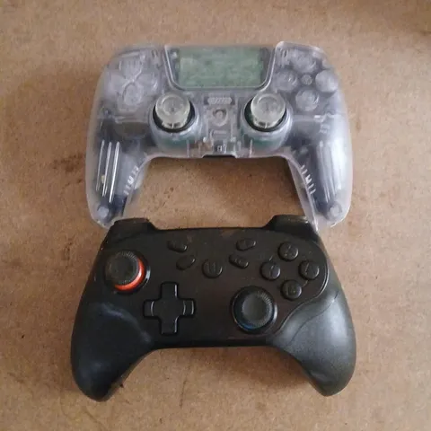 TWO ASSORTED VIDEO GAME CONTROLLERS TO INCLUDE; VIDEO GAME CONTROLLER WITH TRANSPARENT SHELL OVER BLACK BODY