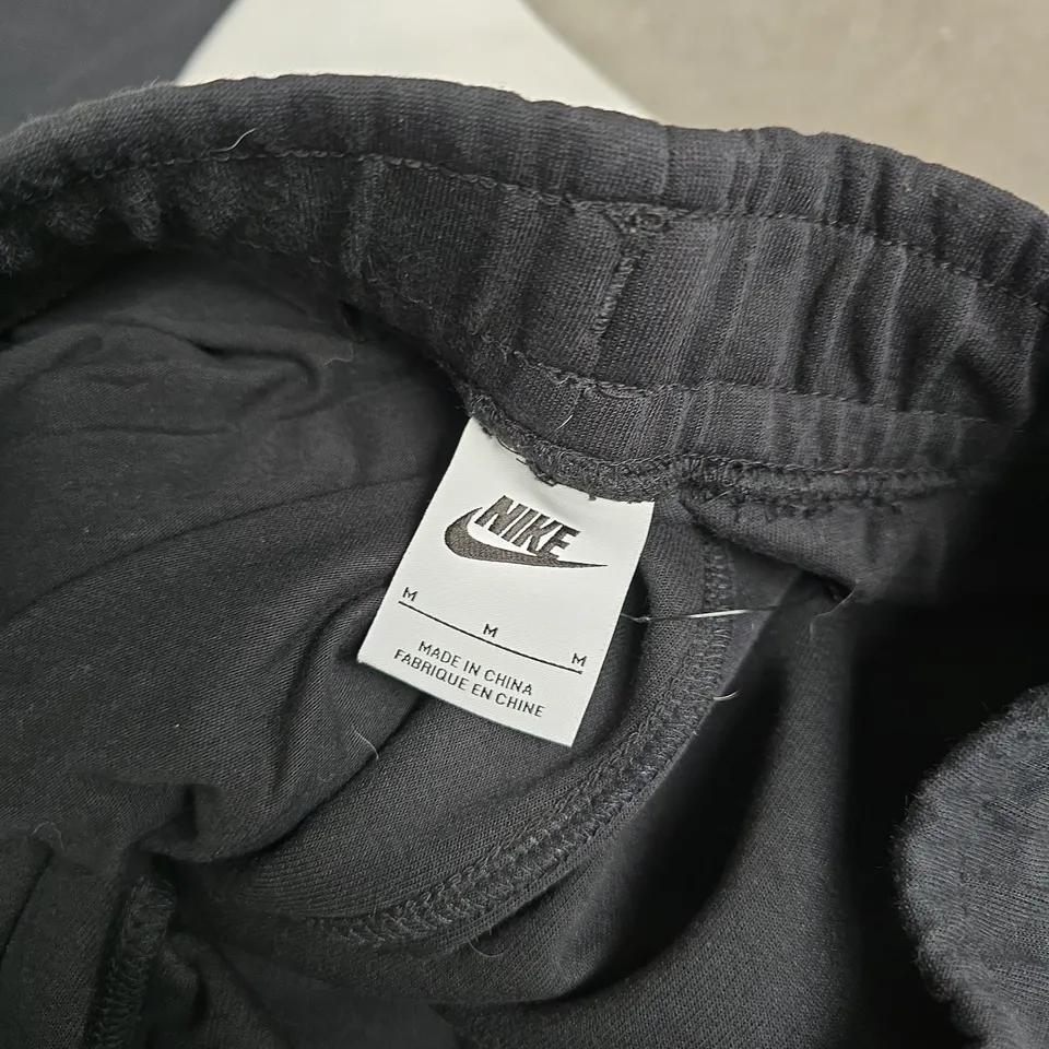 NIKE TRACKPANTS, BLACK WITH WHITE DIAGONAL STRIPE AND SWOOSH – UK MEDIUM (M)