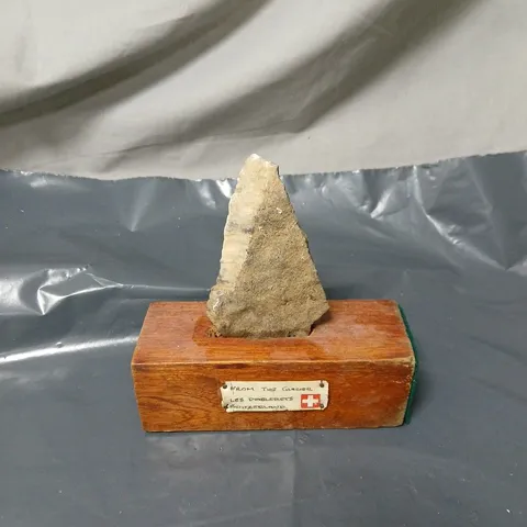 ROCK/MINERAL SPECIMEN ON WOODEN DISPLAY STAND. "FROM THE GLACIER LES DIABLERETS, SWITZERLAND"