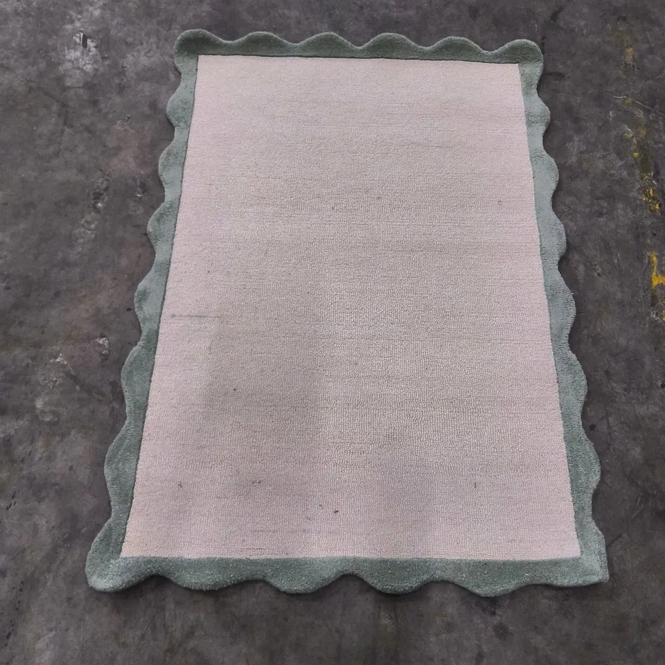 Beige area rug with sage green scalloped border (120x170cm)