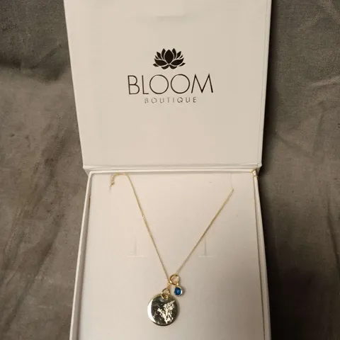 BLOOM BOUTIQUE GOLD-TONE NECKLACE WITH CIRCULAR PENDANT AND BLUE CHARM