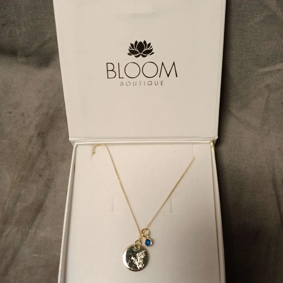 BLOOM BOUTIQUE GOLD-TONE NECKLACE WITH CIRCULAR PENDANT AND BLUE CHARM
