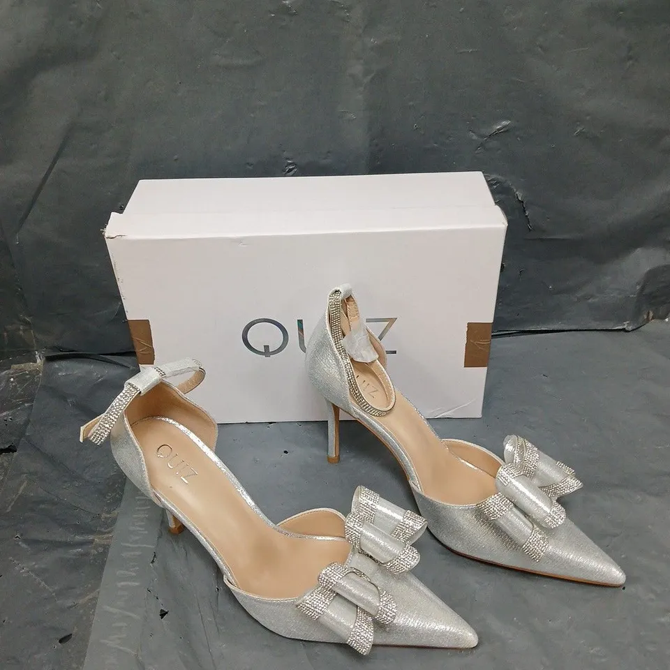 BOXED PAIR OF QUIZ BOW HIGH JEWELLED SILVER HEELS - SIZE 6 