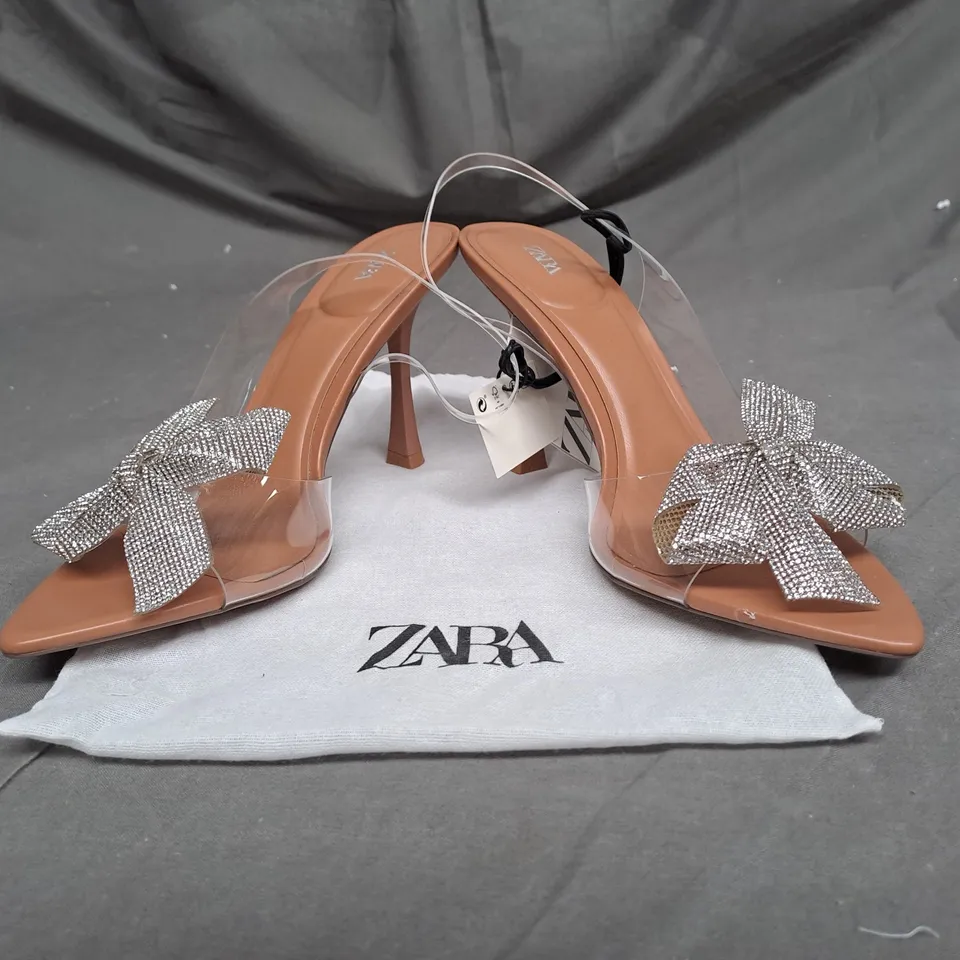 PAIR OF ZARA OPEN TOE HEELS IN CLEAR/TAN WITH SILVER BOW DETAIL SIZE 6