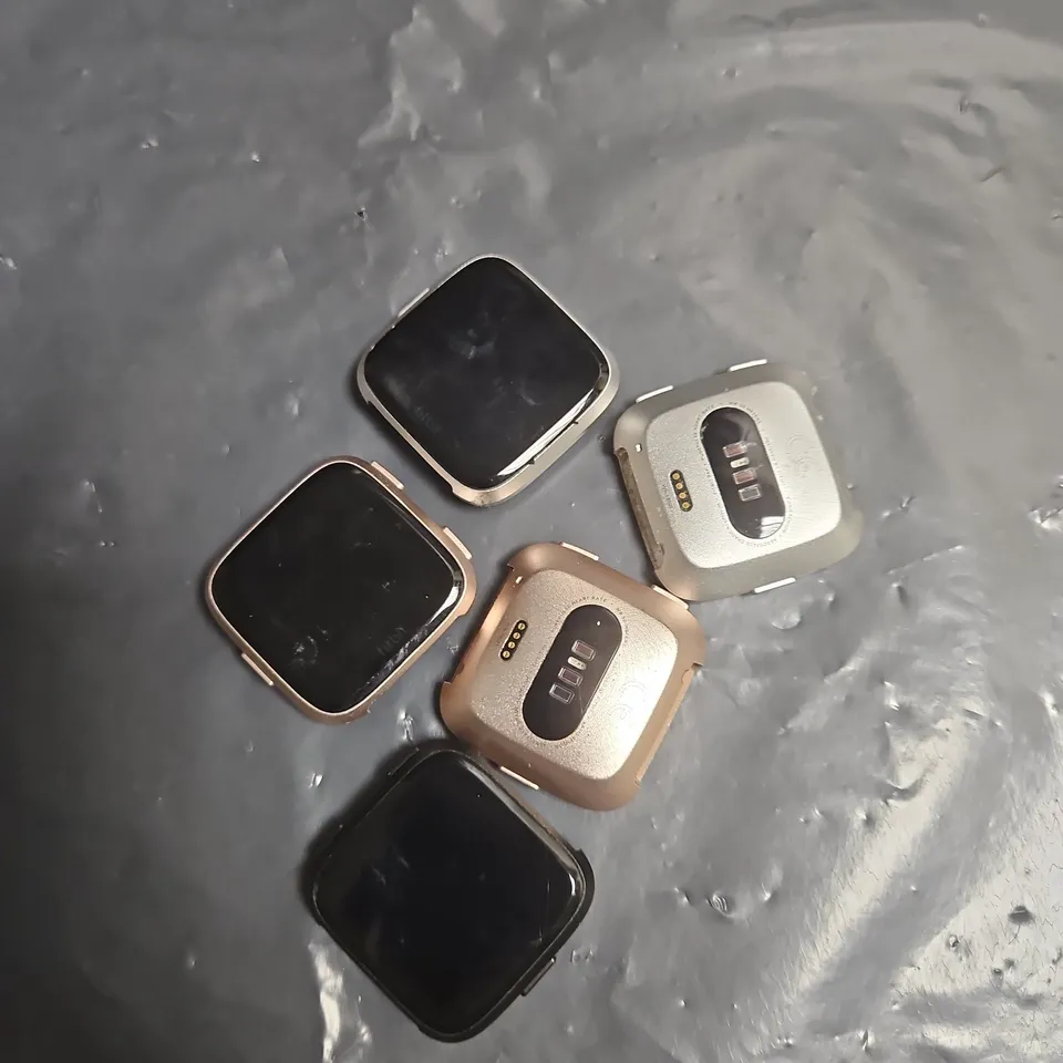 LOT OF APPROXIMATELY 5 FITBIT VERSA WATCHES - ASSORTED COLOURS - NO STRAPS INCLUDED
