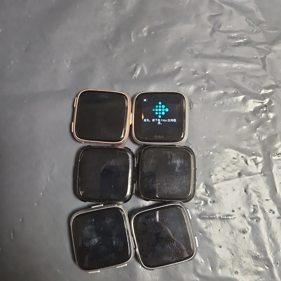 LOT OF APPROXIMATELY 6 FITBIT VERSA WATCHES - ASSORTED COLOURS - NO STRAPS INCLUDED