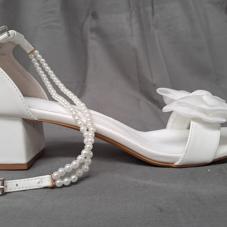 BOXED PAIR OF DESIGNER OPEN TOE BLOCK HEEL BRIDAL STYLE SANDALS IN WHITE W. BOW DETAIL AND PEARL EFFECT STRAP EU SIZE 44