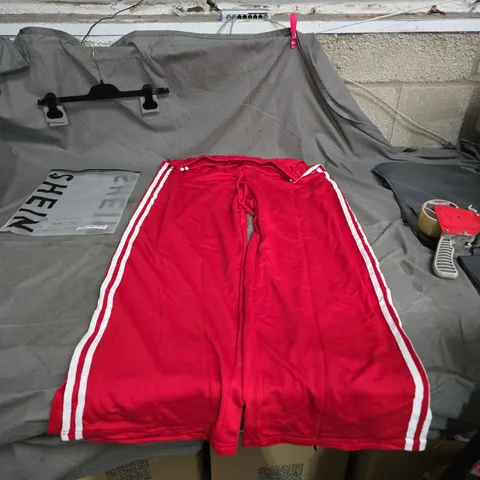 RED ATHLETIC PANTS WITH WHITE PIPING ALONG THE SIDES.