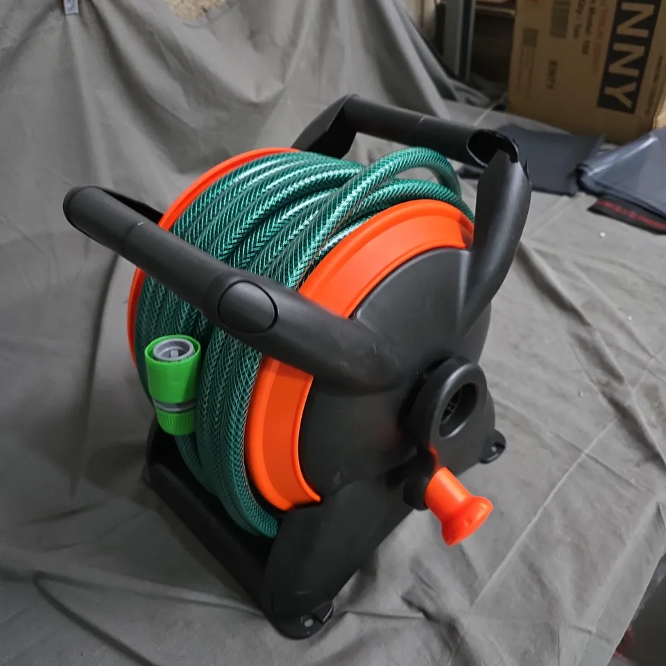 GARDEN HOSE REEL WITH GREEN HOSE, ORANGE DRUM AND SPRAY NOZZLE