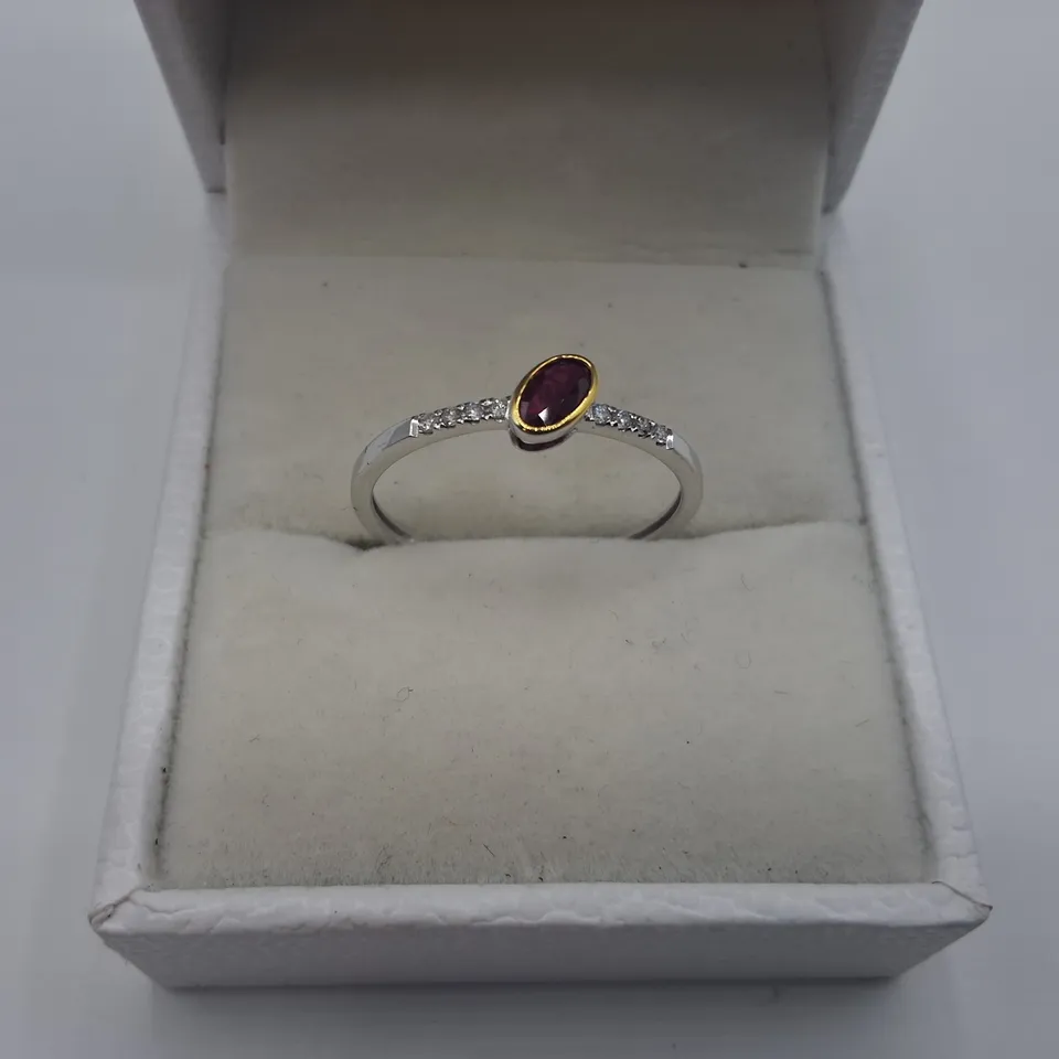 18CT GOLD RING WITH AN OFF-SET ROB OVER OVAL CUT RUBY AND NATURAL DIAMONDS TO EACH SHOULDER