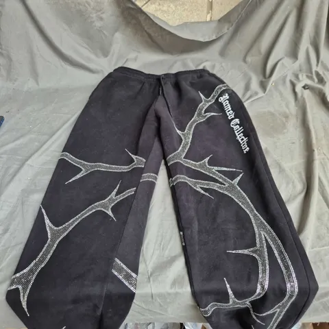 NAMED COLLECTIVE BLACK TRACK PANTS WITH WHITE BRANCH PRINT – ELASTICATED CUFFS