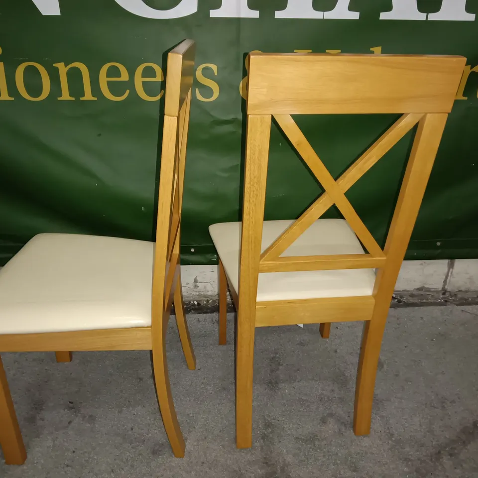 PAIR OF WOODEN CROSS BACK DINING CHAIRS WITH CREAM FAUX LEATHER SEAT PADS