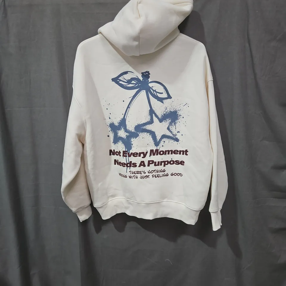 CREAM HOODIE WITH BACK GRAPHIC AND FRONT TEXT – NOT EVERY MOMENT NEEDS A PURPOSE SIZE MEDIUM 