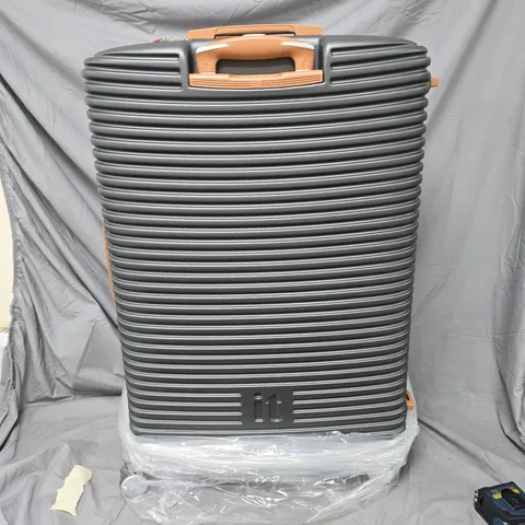 LARGE GREY RIBBED HARD-SHELL SUITCASE WITH ORANGE HANDLES. IT BRANDED
