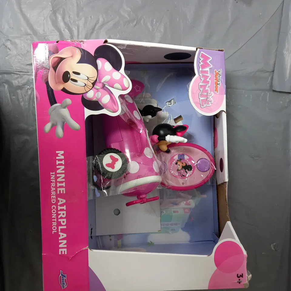 A SELECTION OF GOODS TO INCLUDE A TRAVEL BARBIE AND DOG, A MINNIE MOUSE AIRPLANE AND A SET OF MEASURING SPOONS.