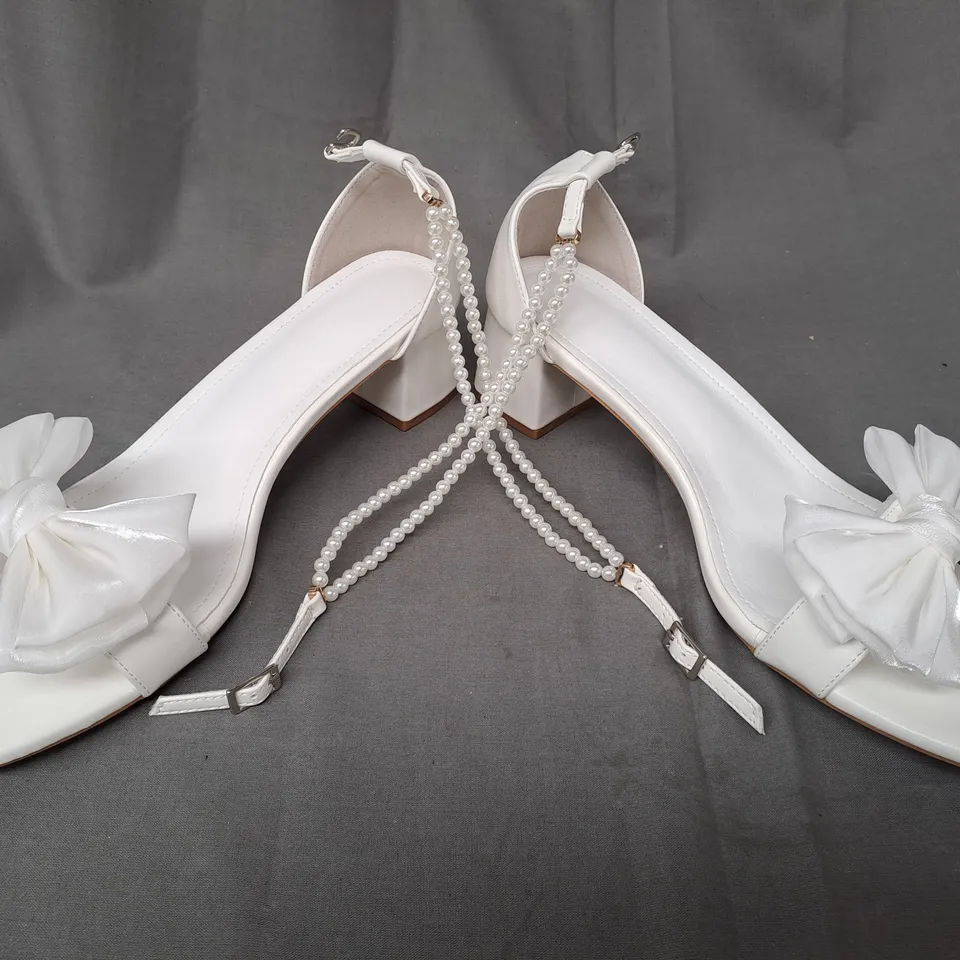 BOXED PAIR OF DESIGNER OPEN TOE BLOCK HEEL BRIDAL STYLE SANDALS IN WHITE W. BOW DETAIL AND PEARL EFFECT STRAP EU SIZE 44