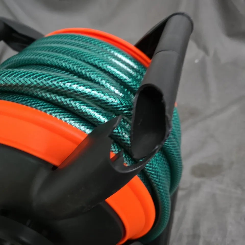 GARDEN HOSE REEL WITH GREEN HOSE, ORANGE DRUM AND SPRAY NOZZLE