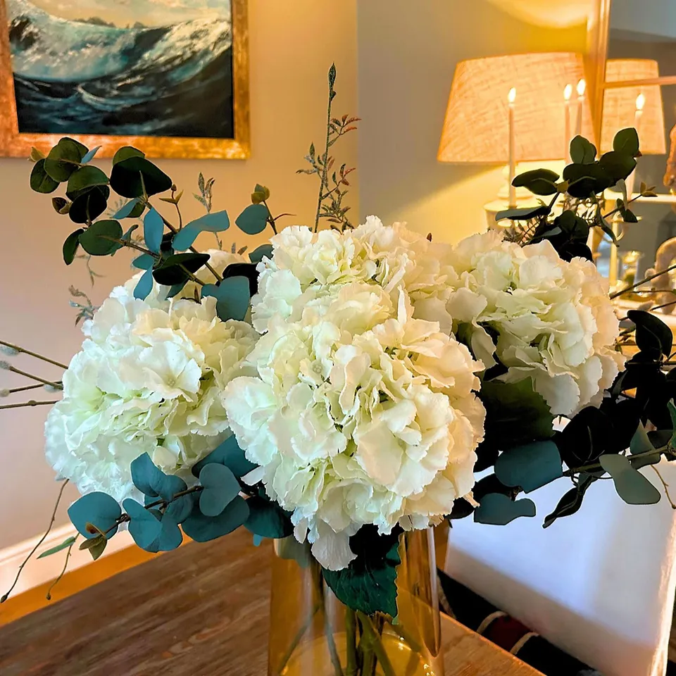 PEONY HYDRANGEAS & FOLIAGE IN AN AMBER FOOTED VASE