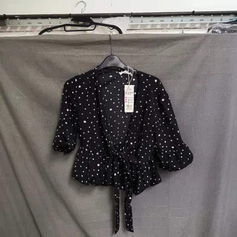 BOX OF APPROXIMATELY 50 URBAN BLISS WOMEN'S BLACK POLKA DOT WRAP BLOUSE WITH TIE-WAIST - SIZES 8 / 10 /12 / 14 