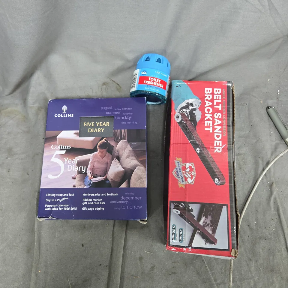A TOTE OF ASSORTED ITEMS TO INCLUDE– BELT SANDER BRACKET, COLLINS FIVE YEAR DIARY, 2026 PLANNER, AND MISC ITEMS
