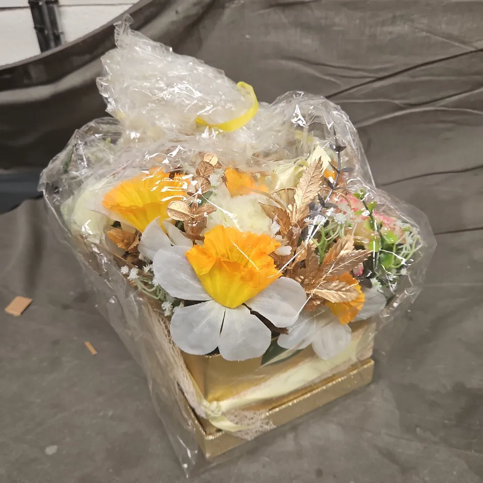 ARTIFICIAL FLOWER ARRANGEMENT IN GOLD BASE, WRAPPED IN CLEAR PLASTIC