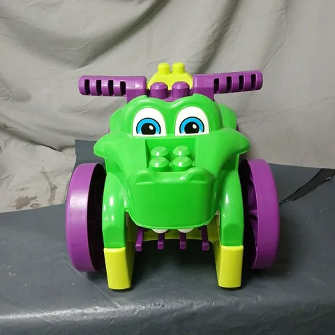 CHILDREN'S PLASTIC RIDE-ON TOY VEHICLE – GREEN WITH PURPLE WHEELS, EXTRA TOYS INSIDE. UNBOXED