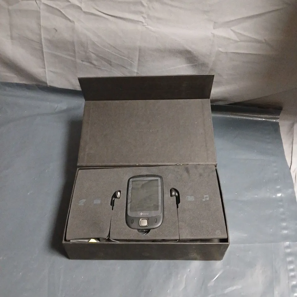 HTC SMARTPHONE IN BOXED PACKAGING – FOAM INSERTS AND HEADSET-LIKE ACCESSORIES 